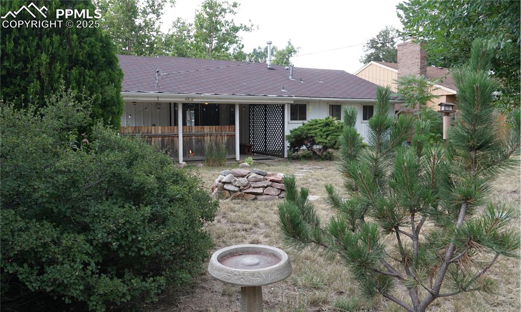 Image 18 of 23: Back yard with lots of foliage and a covered patio to enjoy it from