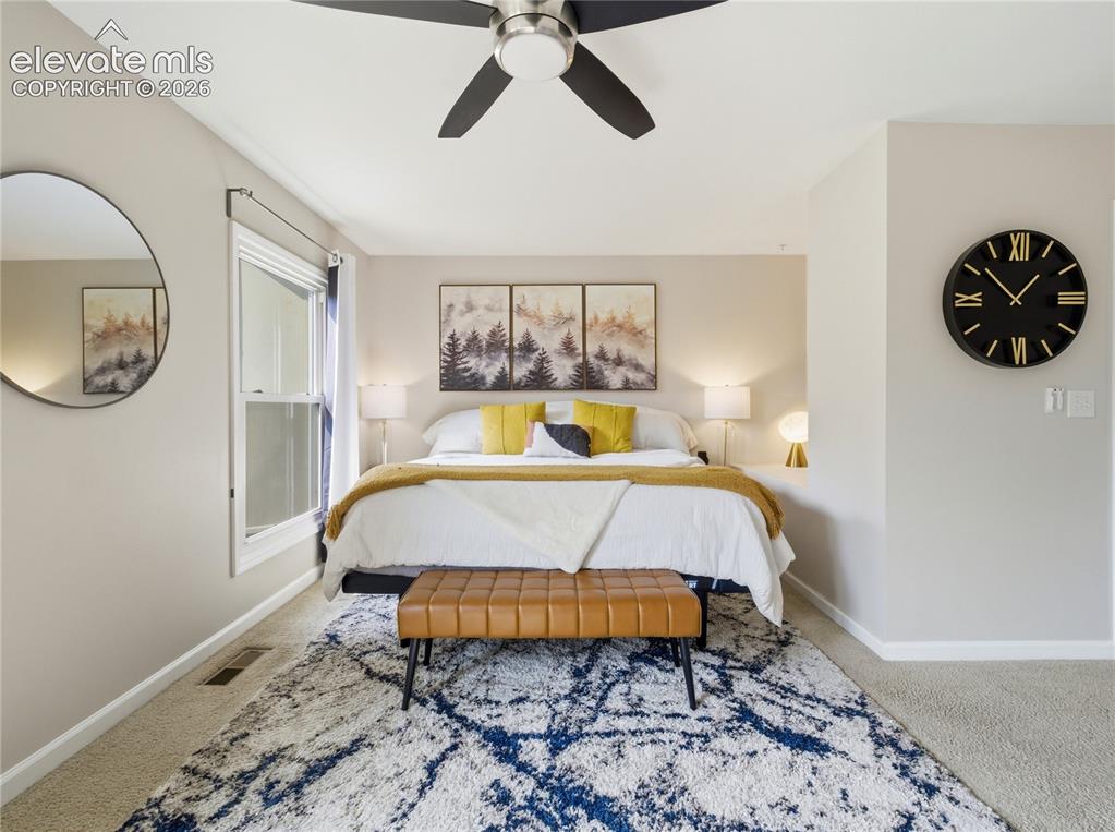 Image 16 of 29: Ceiling fan with matte black blades, window with white trim, and light-colo