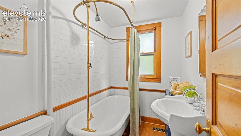 Image 13 of 38: Bathroom featuring a clawfoot tub with a brass shower fixture, subway tile
