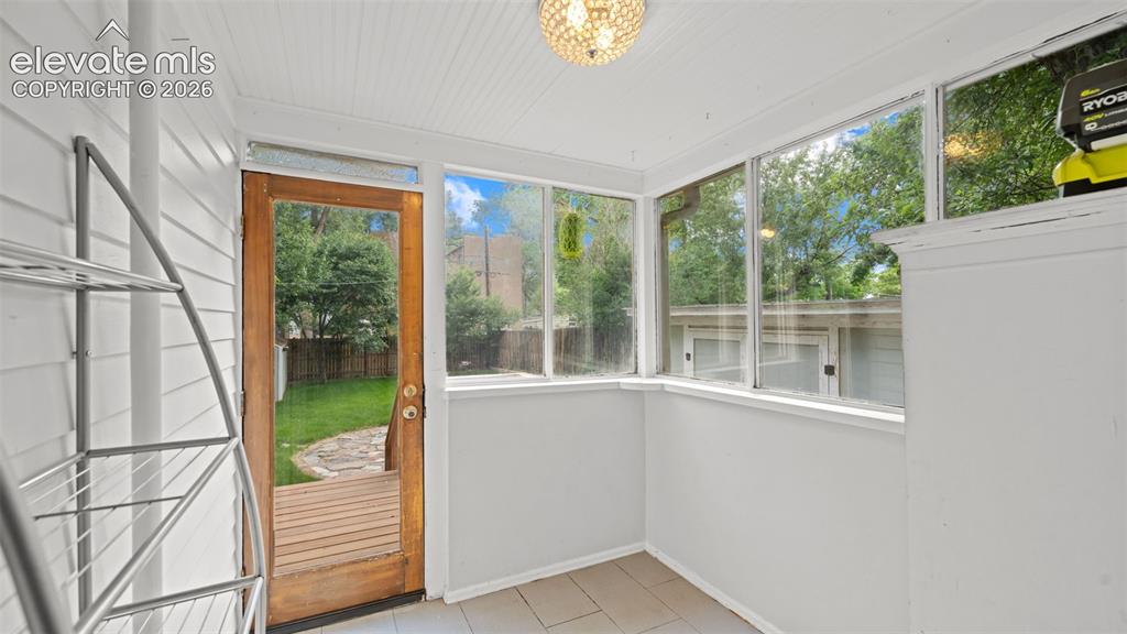 Image 17 of 38: Enclosed sunroom featuring multiple large windows, tile flooring, a wood-pa