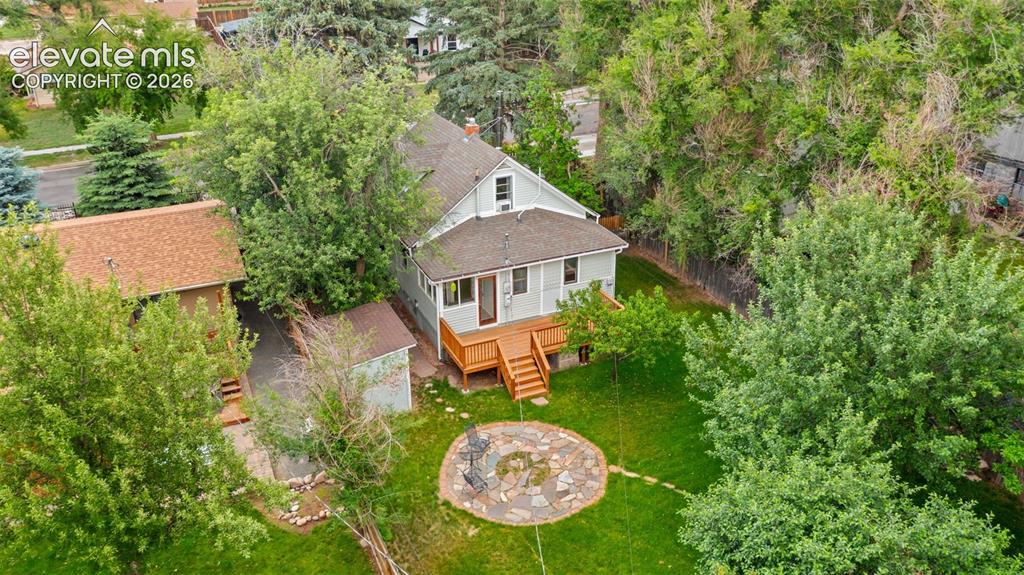 Image 33 of 38: Rear exterior featuring a multi-level wood deck, a flagstone patio with a c