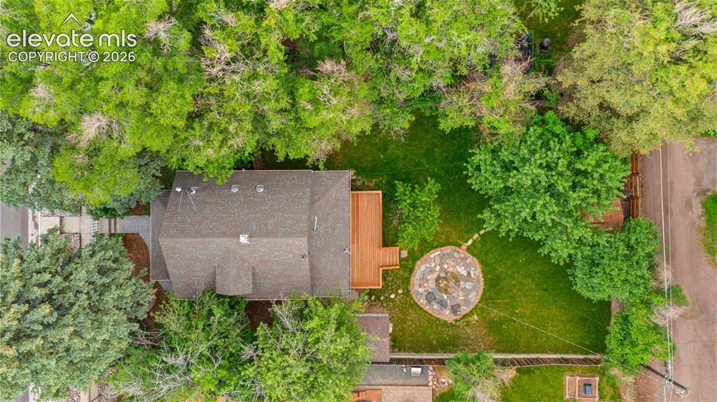 Image 34 of 38: Expansive backyard featuring a manicured lawn, mature trees, a multi-level