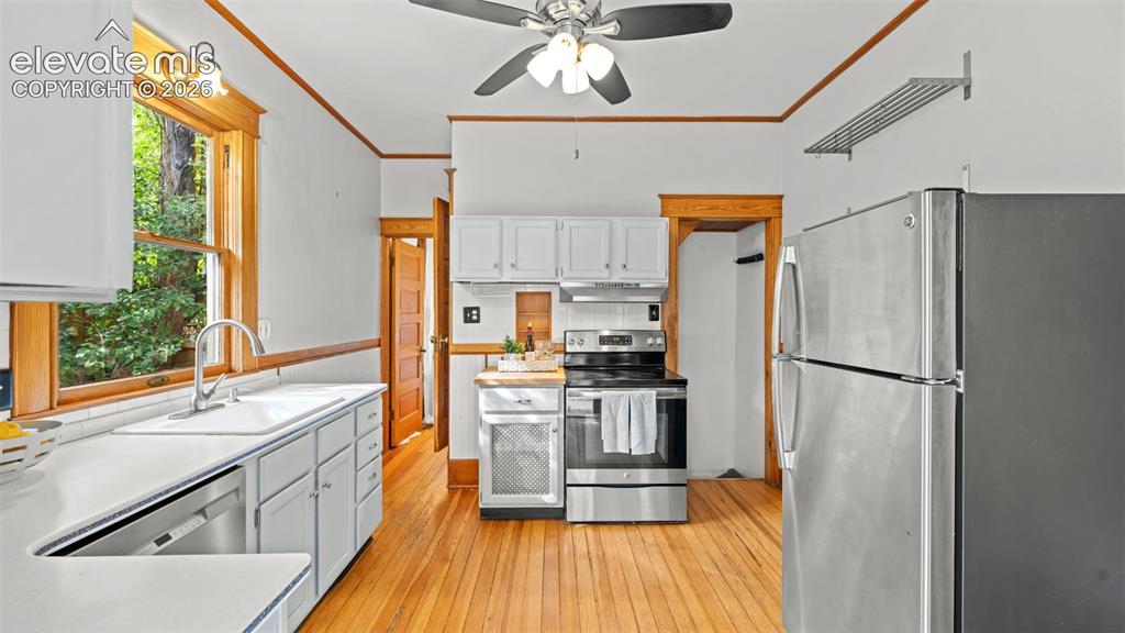 Image 4 of 38: Kitchen featuring wood-finish flooring, white cabinetry, a stainless steel
