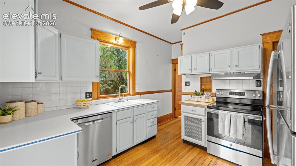 Image 5 of 38: Kitchen featuring wood-finish flooring, white cabinetry, a white subway til