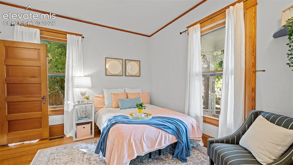 Image 8 of 38: Bedroom with natural light, wood-finish flooring, and a five-panel wood doo