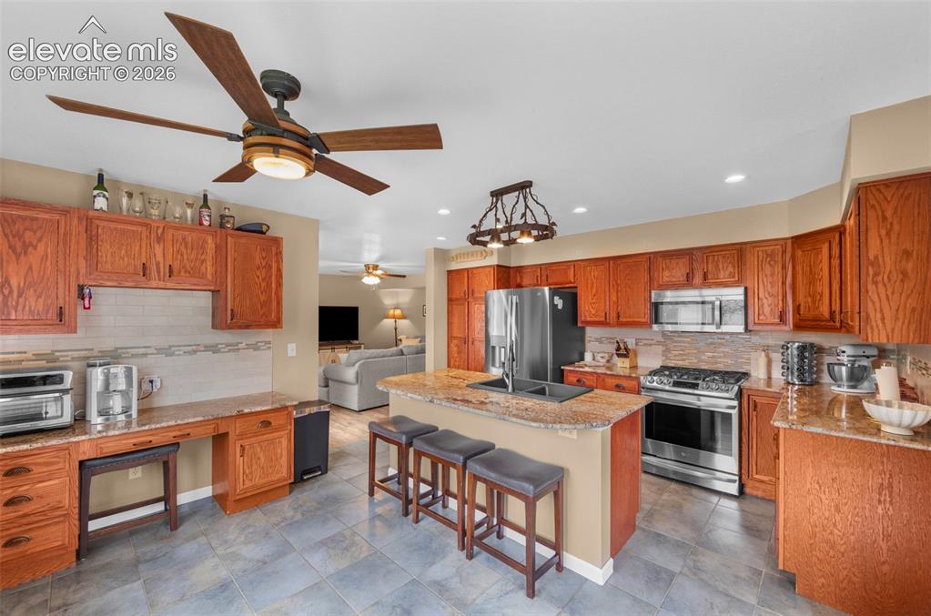 Image 10 of 41: Kitchen featuring wood cabinetry, light-toned countertops, a central island