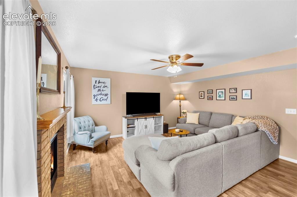 Image 12 of 41: Living area featuring wood-finish flooring, a brick fireplace with a wood m