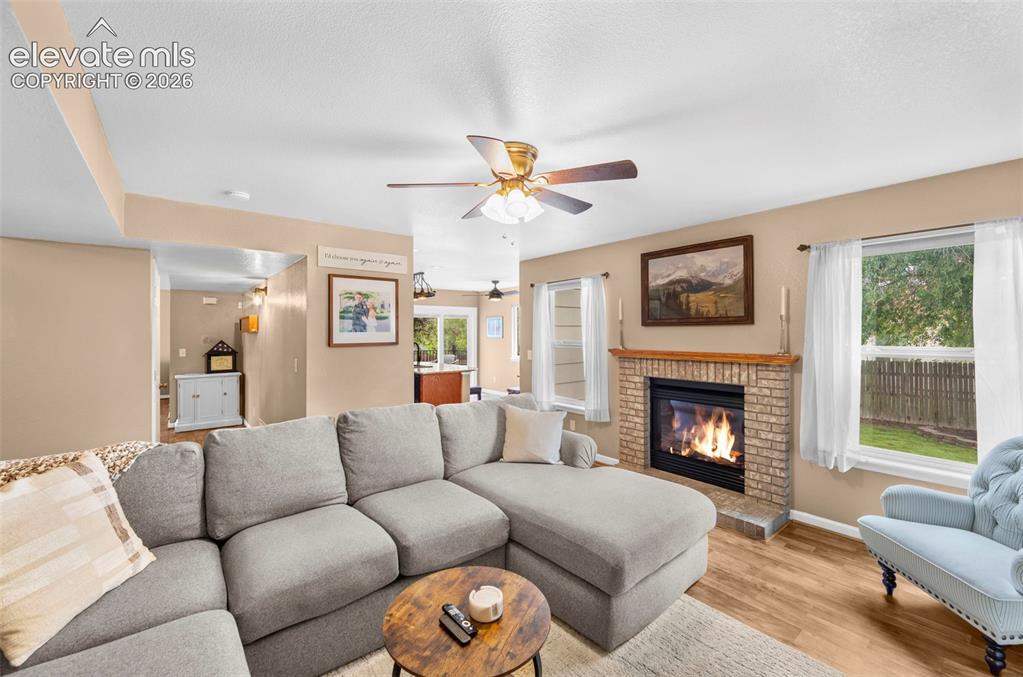 Image 14 of 41: Living area featuring a brick fireplace with a wood mantel, wood-finish flo
