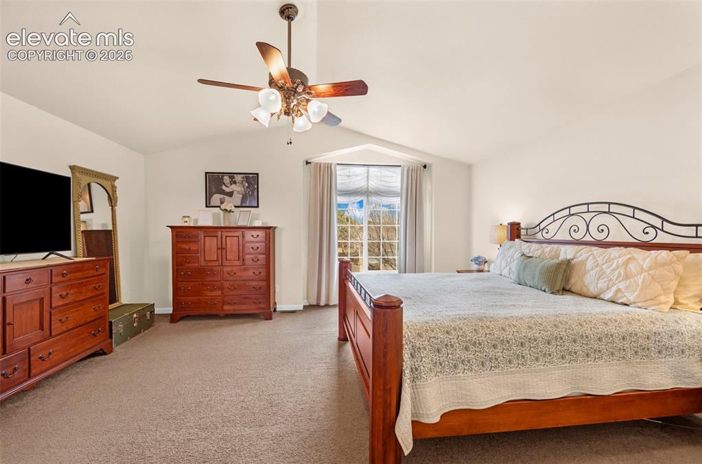Image 20 of 41: Vaulted ceiling bedroom with a prominent large window, soft neutral wall to
