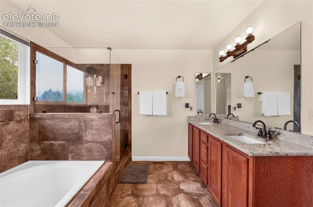 Image 22 of 41: Bathroom featuring a large soaking tub with a tiled surround, a glass-enclo