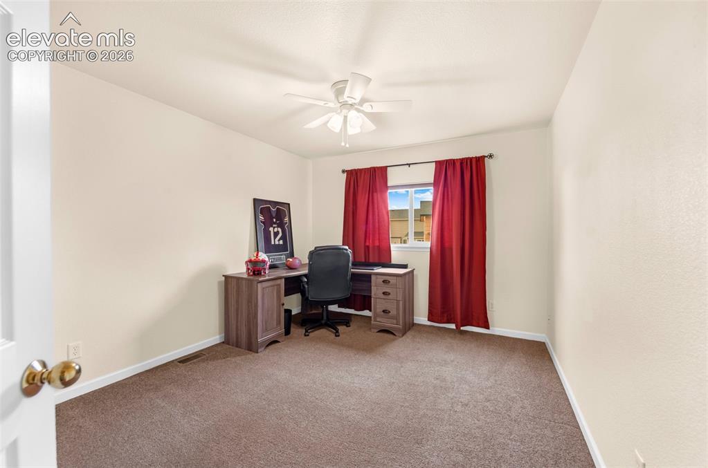 Image 23 of 41: Bright room featuring a window with red drapery, light-colored walls, and b