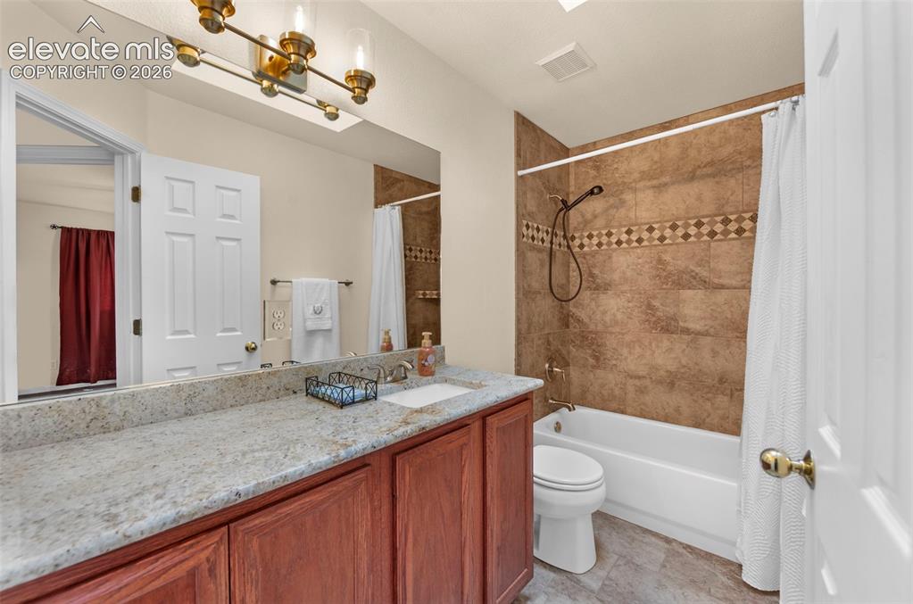 Image 24 of 41: Bathroom featuring a wood-finish vanity with a light speckled countertop, s