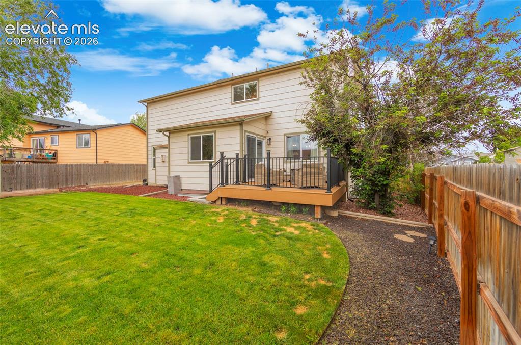 Image 28 of 41: Expansive backyard featuring a manicured lawn, wood fencing, and a gravel p