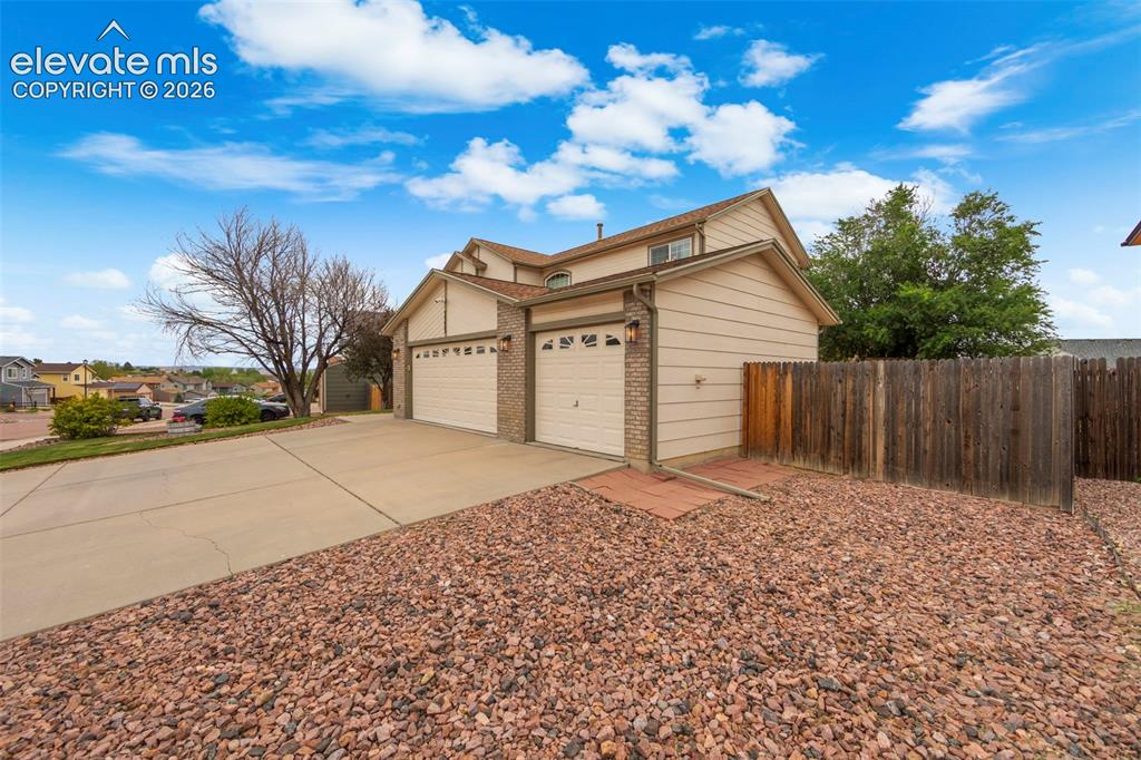 Image 3 of 41: Two-story residence featuring a two-car garage with overhead doors, brick a