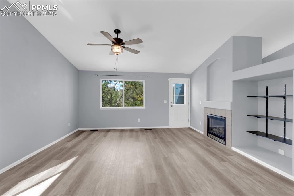 Image 10 of 36: Living room featuring ceiling fan, gas fireplace, built in shelves & walk o