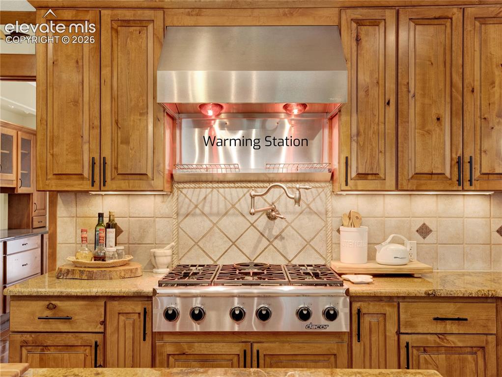 Image 12 of 43: Top of the line dacor stove top with pot filler and warming station above