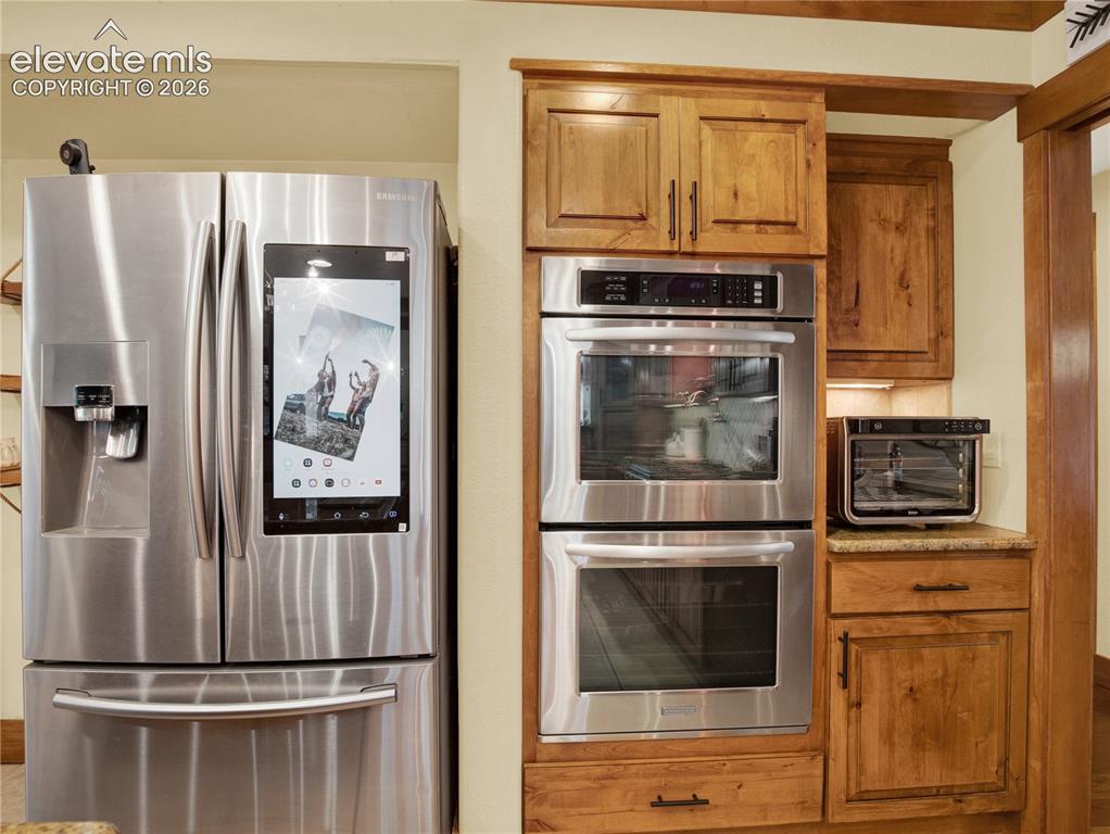 Image 13 of 43: Kitchen Aid double oven aside a smart Samsung refrigerator