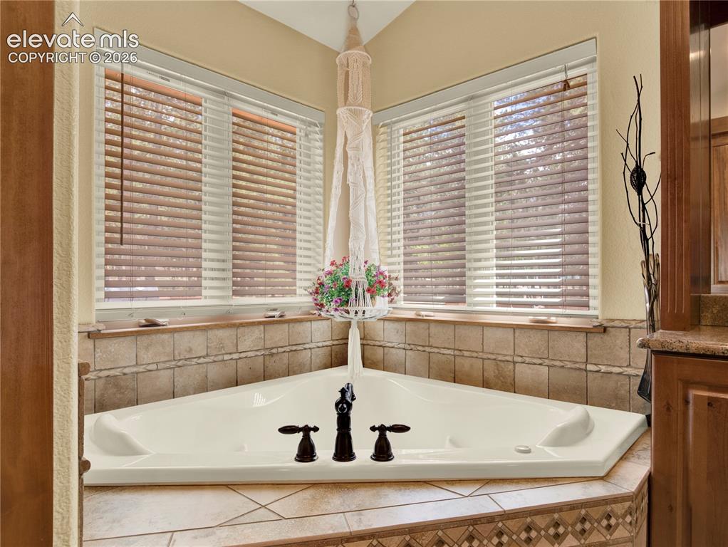 Image 22 of 43: Large soaking heated and jetted tub in the corner of the primary bathroom