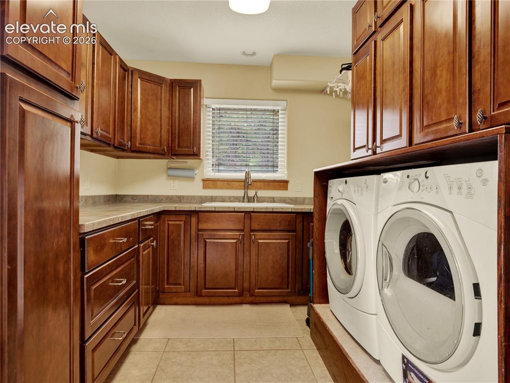 Image 28 of 43: Large laundry room on the main level with a utility sink and a ample storag