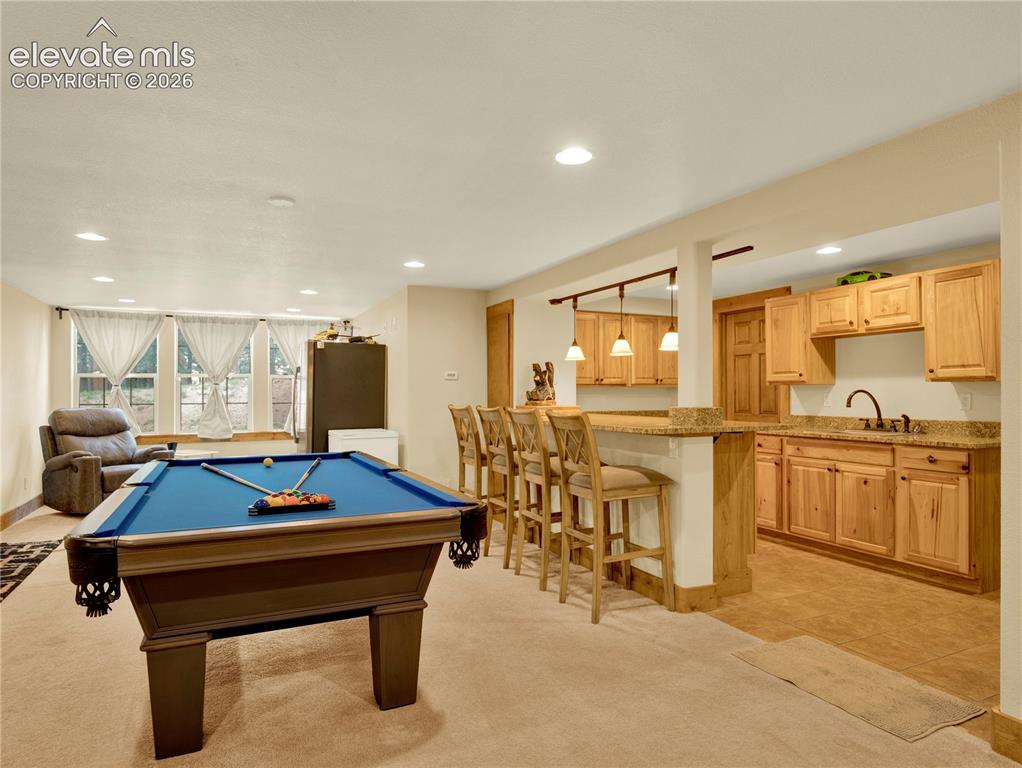Image 31 of 43: Lower level entertainment space with full wet bar and space for a pool tabl