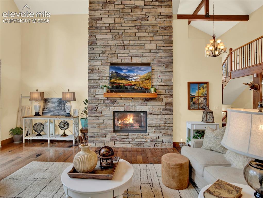Image 8 of 43: Stone fireplace, to the left is the floor to ceiling windows with doors to