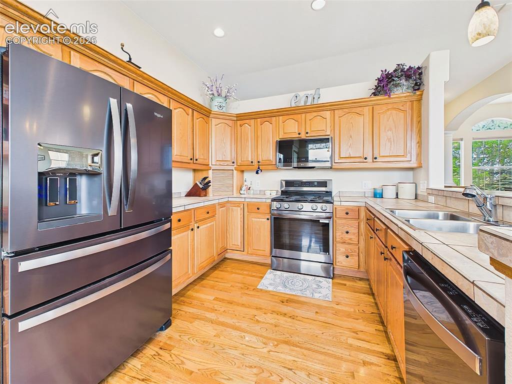 Image 13 of 50: Well-appointed kitchen with tile countertops, recessed lighting, under-coun