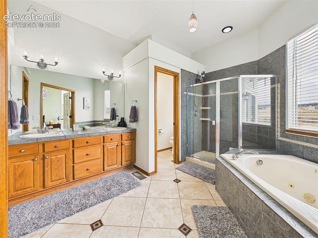 Image 18 of 50: Spa-inspired primary bath featuring dual vanities, a soaking tub, separate