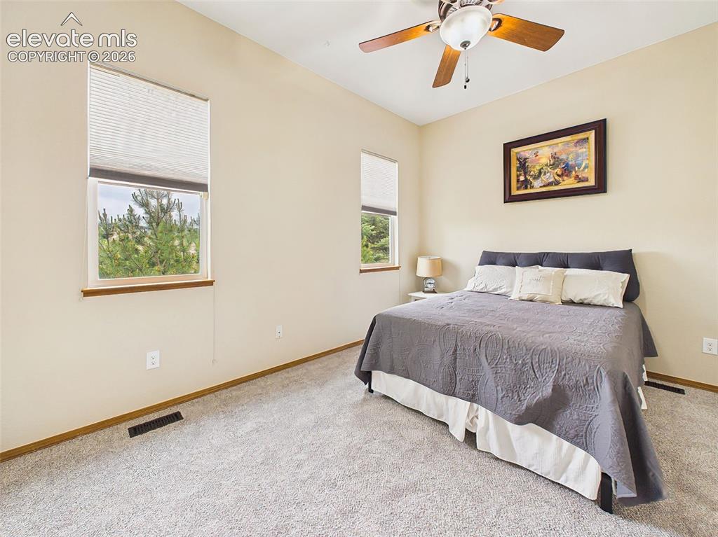Image 20 of 50: Bright main level bedroom featuring neutral tones, large windows, and a coz
