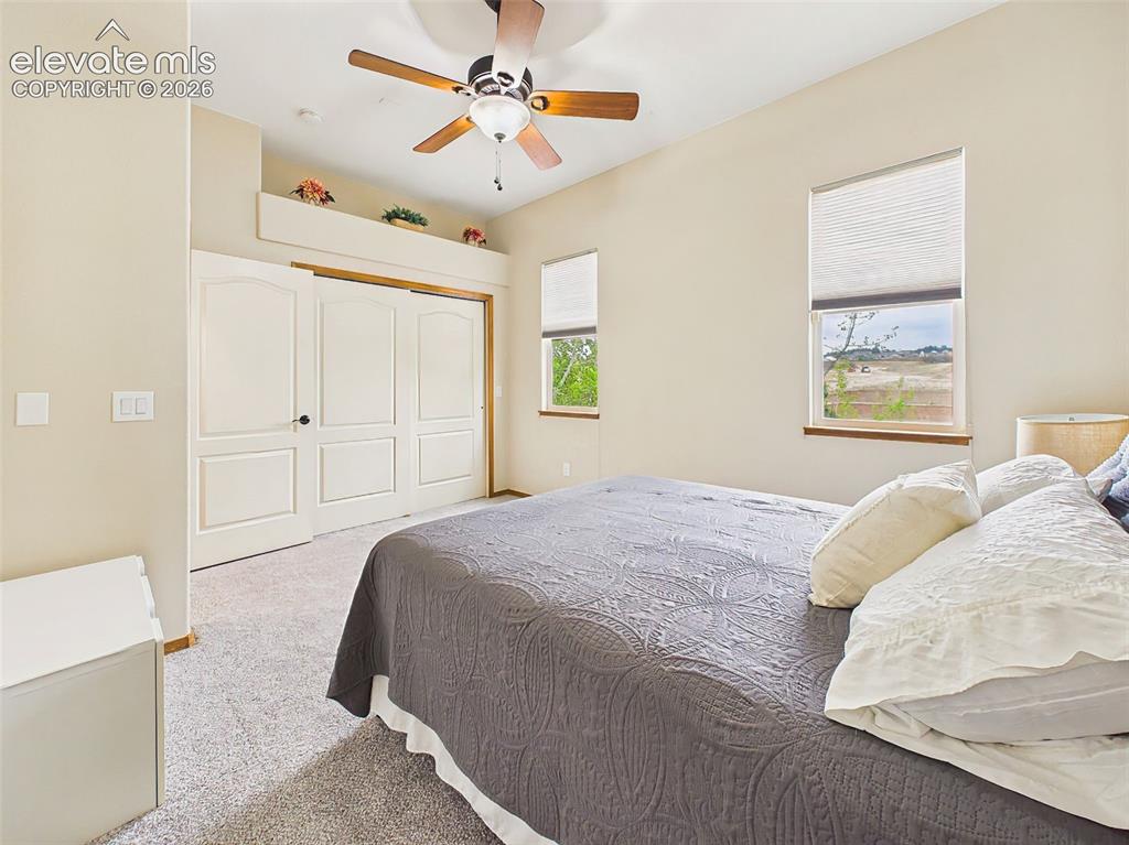 Image 21 of 50: Comfortable secondary bedroom with soft carpeting, ceiling fan, and ample c