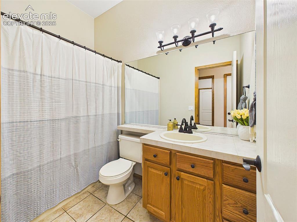 Image 22 of 50: Well-maintained full bath with tile countertops, and a convenient tub/showe