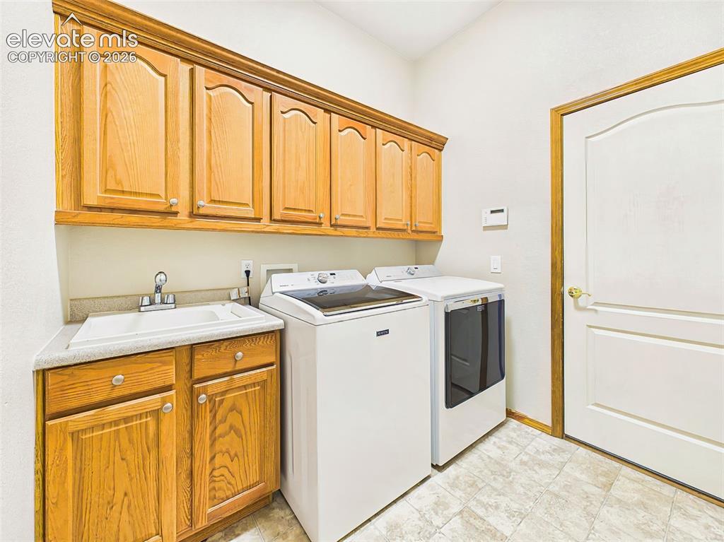 Image 23 of 50: Dedicated laundry room with built-in cabinetry, utility sink, and additiona