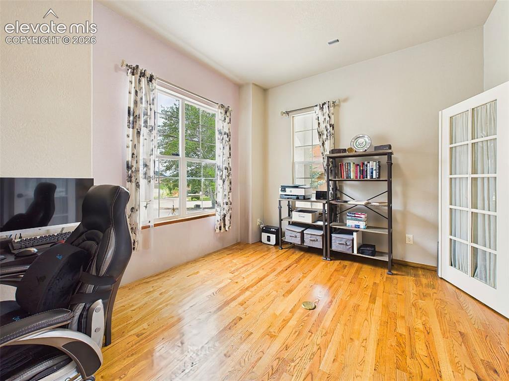 Image 25 of 50: Bright main-level office featuring large windows, hardwood floors, and Fren