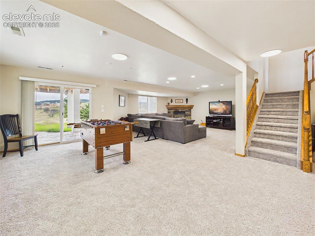 Image 26 of 50: Expansive lower-level living area with plush carpeting, fireplace, and walk