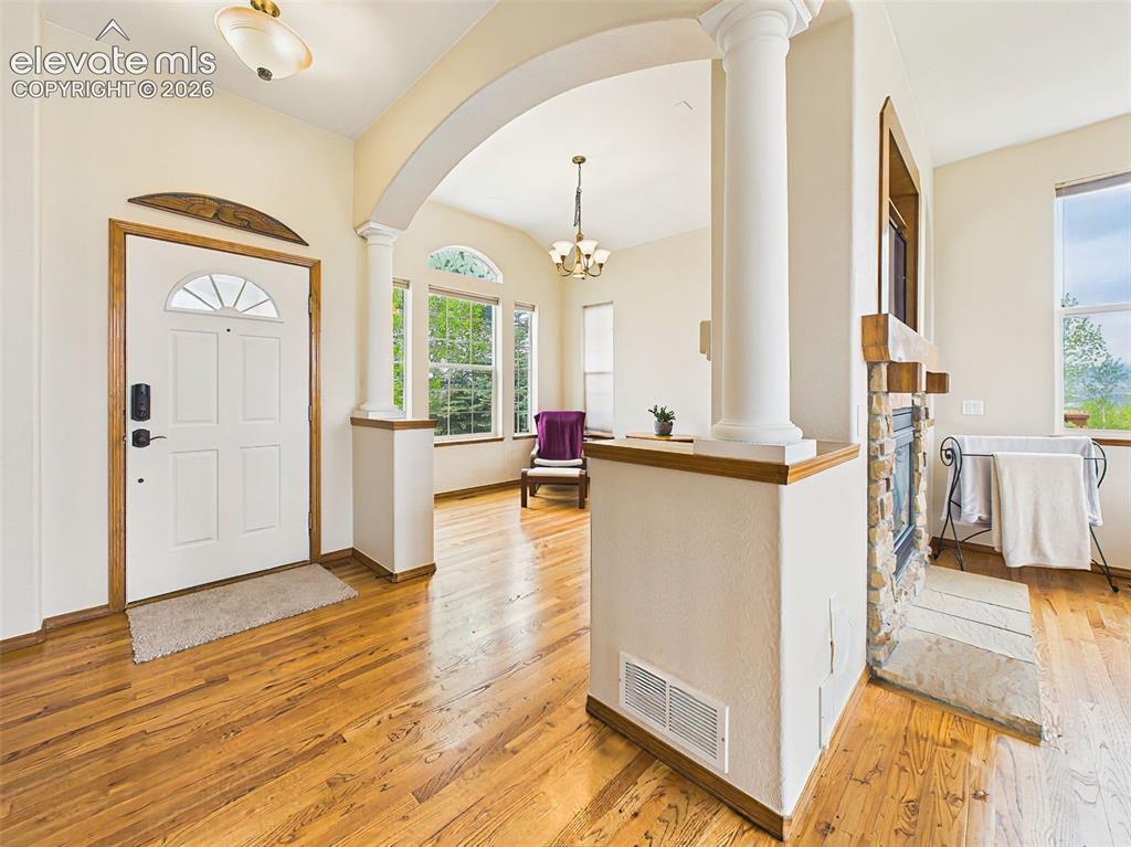 Image 3 of 50: Bright and inviting entryway with warm hardwood flooring, elegant columns,
