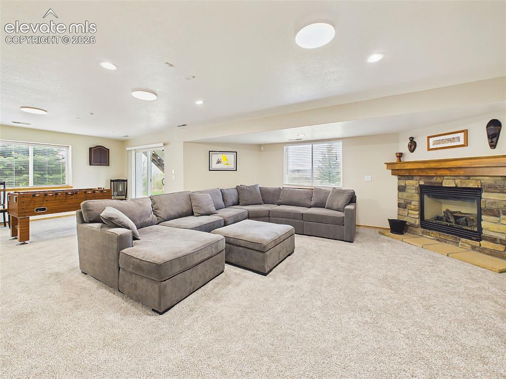 Image 30 of 50: Warm and welcoming entertainment space centered around a beautiful stone fi