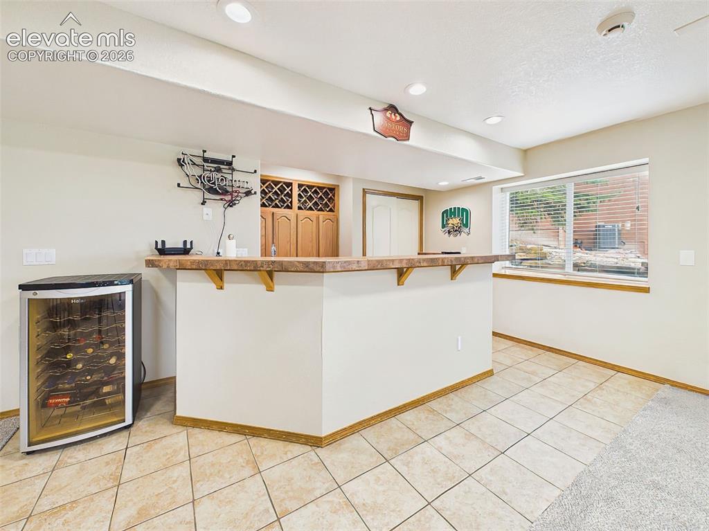 Image 31 of 50: Entertainer’s wet bar with wraparound counter seating and built-in wine sto