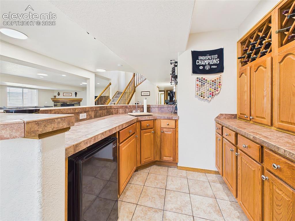 Image 32 of 50: Functional lower-level bar area with extensive cabinetry, prep space, and c