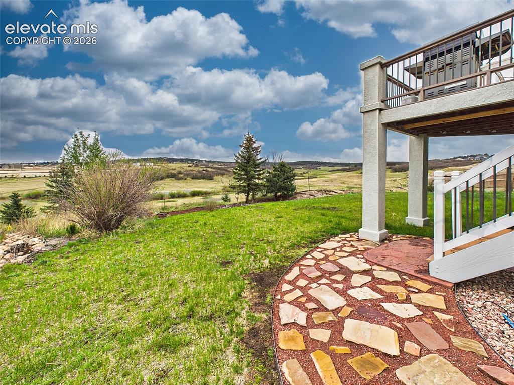 Image 42 of 50: Expansive backyard with custom stone pathways and direct access to wide-ope