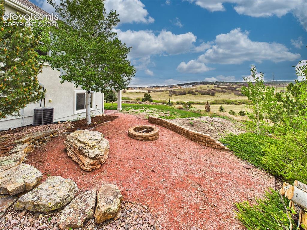 Image 44 of 50: Landscaped outdoor retreat featuring a built-in fire pit area and scenic op