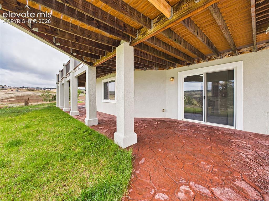 Image 45 of 50: Large covered patio with stamped concrete flooring offers shaded outdoor li