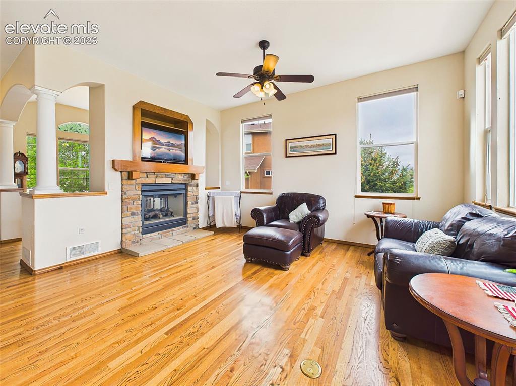 Image 6 of 50: Spacious main living area with hardwood flooring, architectural columns, an