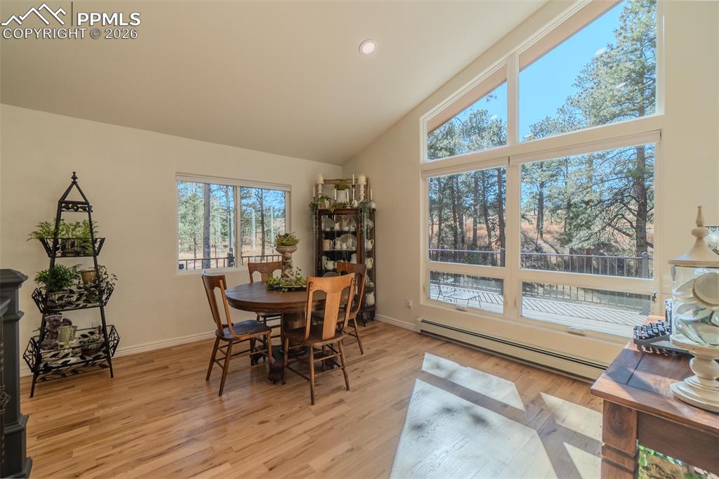 Image 12 of 50: Dining space with a baseboard heating unit, light wood-style floors, lofted