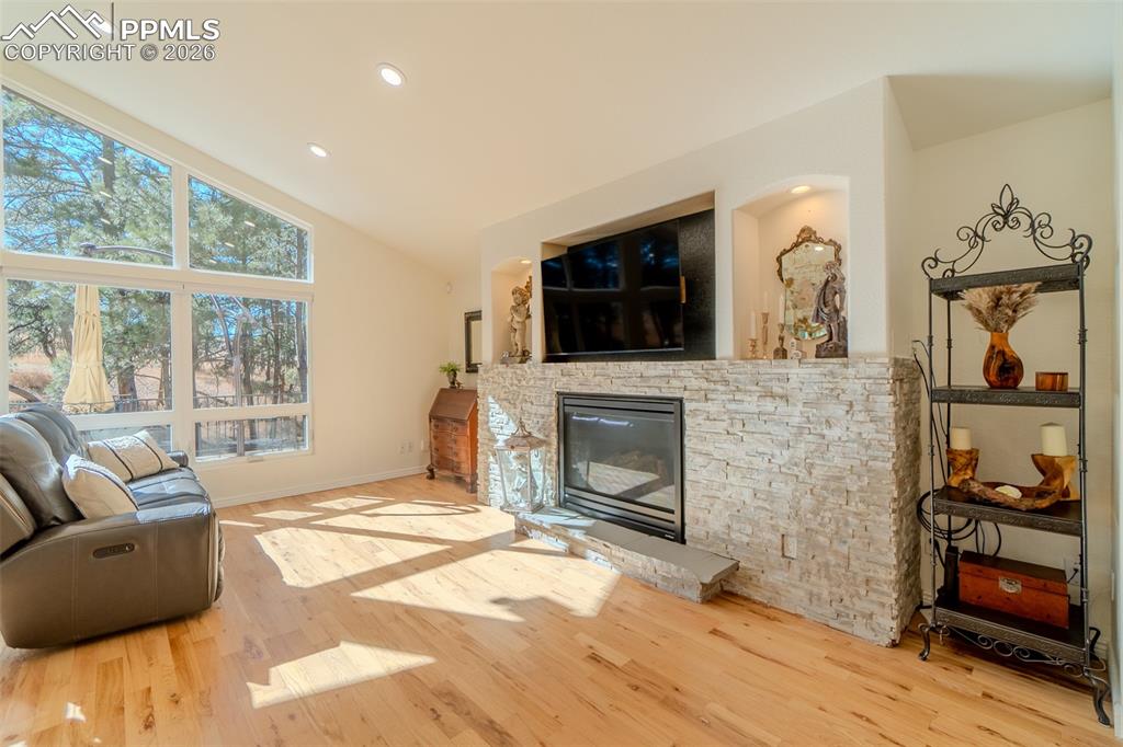 Image 15 of 50: Living room featuring light wood finished floors, a fireplace, lofted ceili