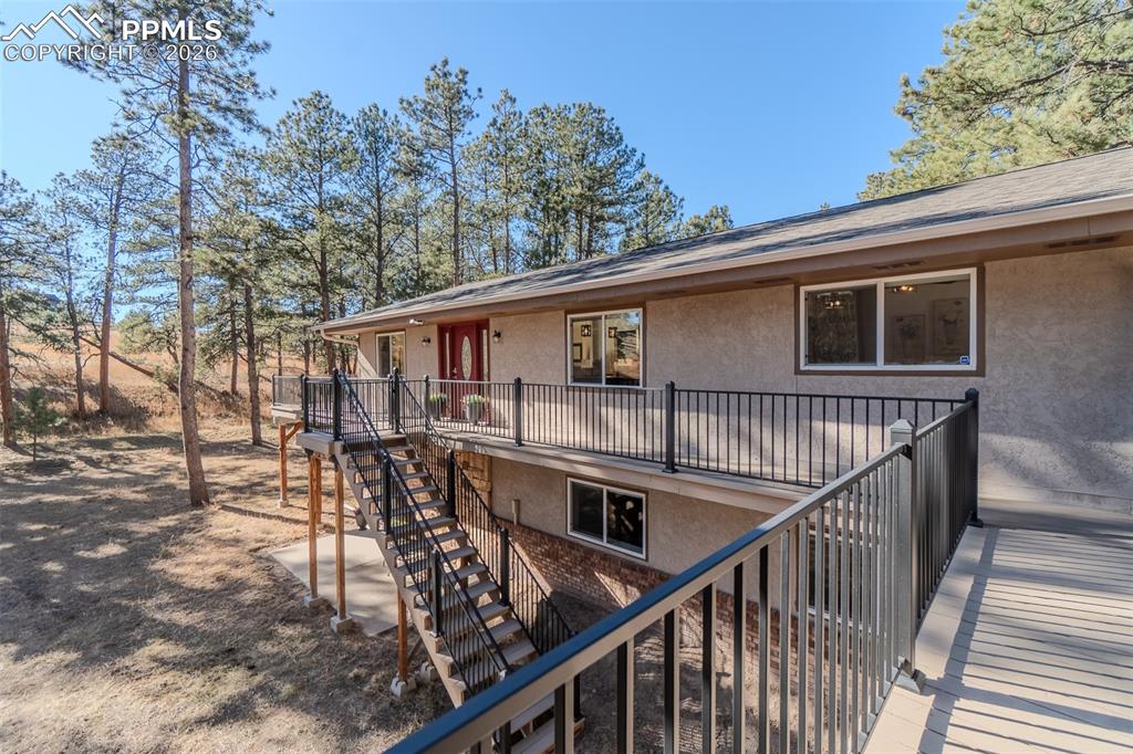 Image 42 of 50: Rear view of property with stairs and stucco siding
