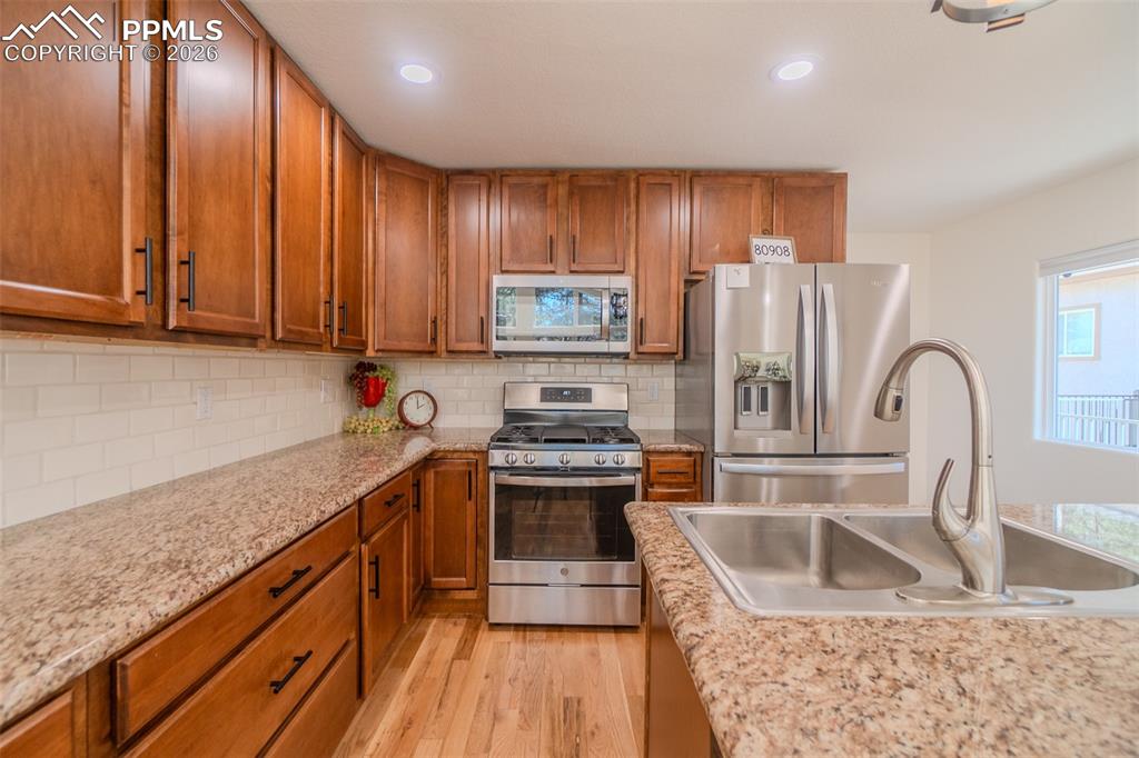 Image 9 of 50: Kitchen featuring granite countertops, stainless steel appliances, wood fin
