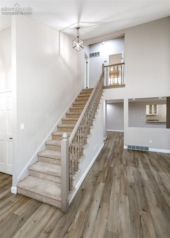 Image 10 of 44: Open living space featuring wood-finish flooring, a carpeted staircase with