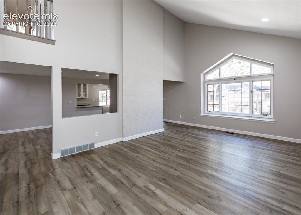 Image 12 of 44: Vaulted ceilings, wood-finish flooring, a large arched window with grid det