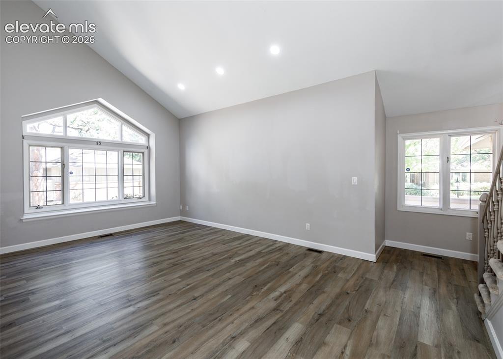 Image 13 of 50: Vaulted ceiling with recessed lighting, wood-finish flooring, and a large a