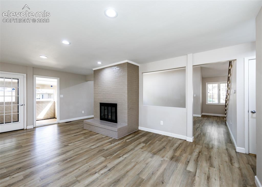 Image 14 of 44: Living area featuring wood-finish flooring, recessed lighting, a brick fire