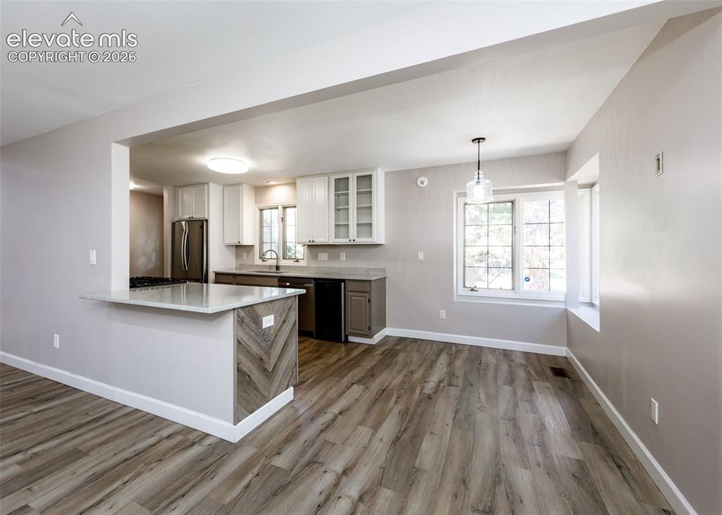 Image 18 of 44: Wood-finish flooring throughout, kitchen with light-tone upper cabinetry, l